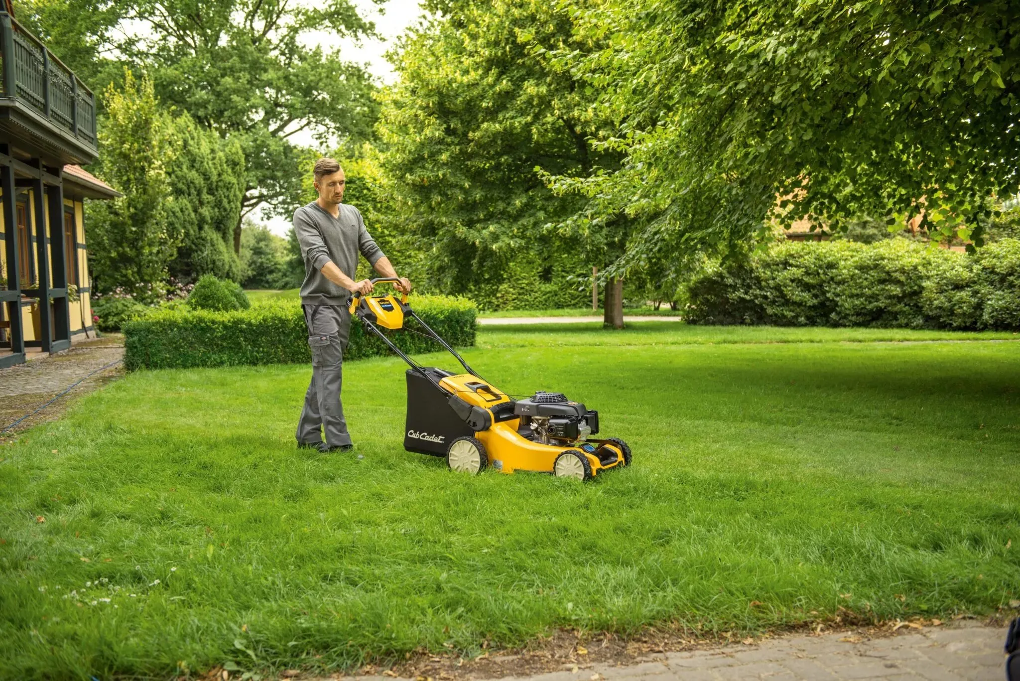 Man mowing a lush green lawn with a yellow lawn mower, representing professional lawn mowing and lawn care services.